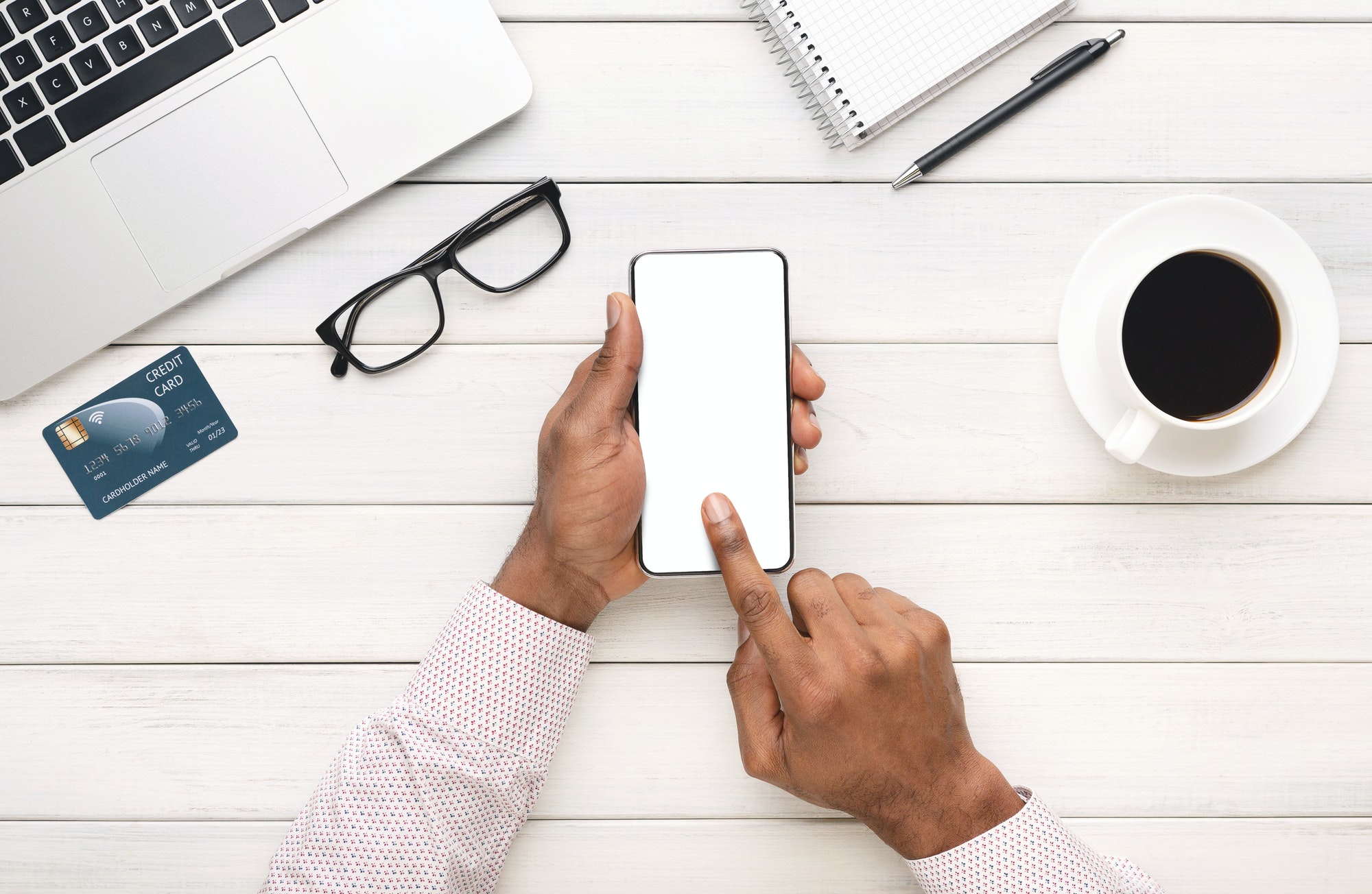 Black hands using smartphone with blank screen at workplace