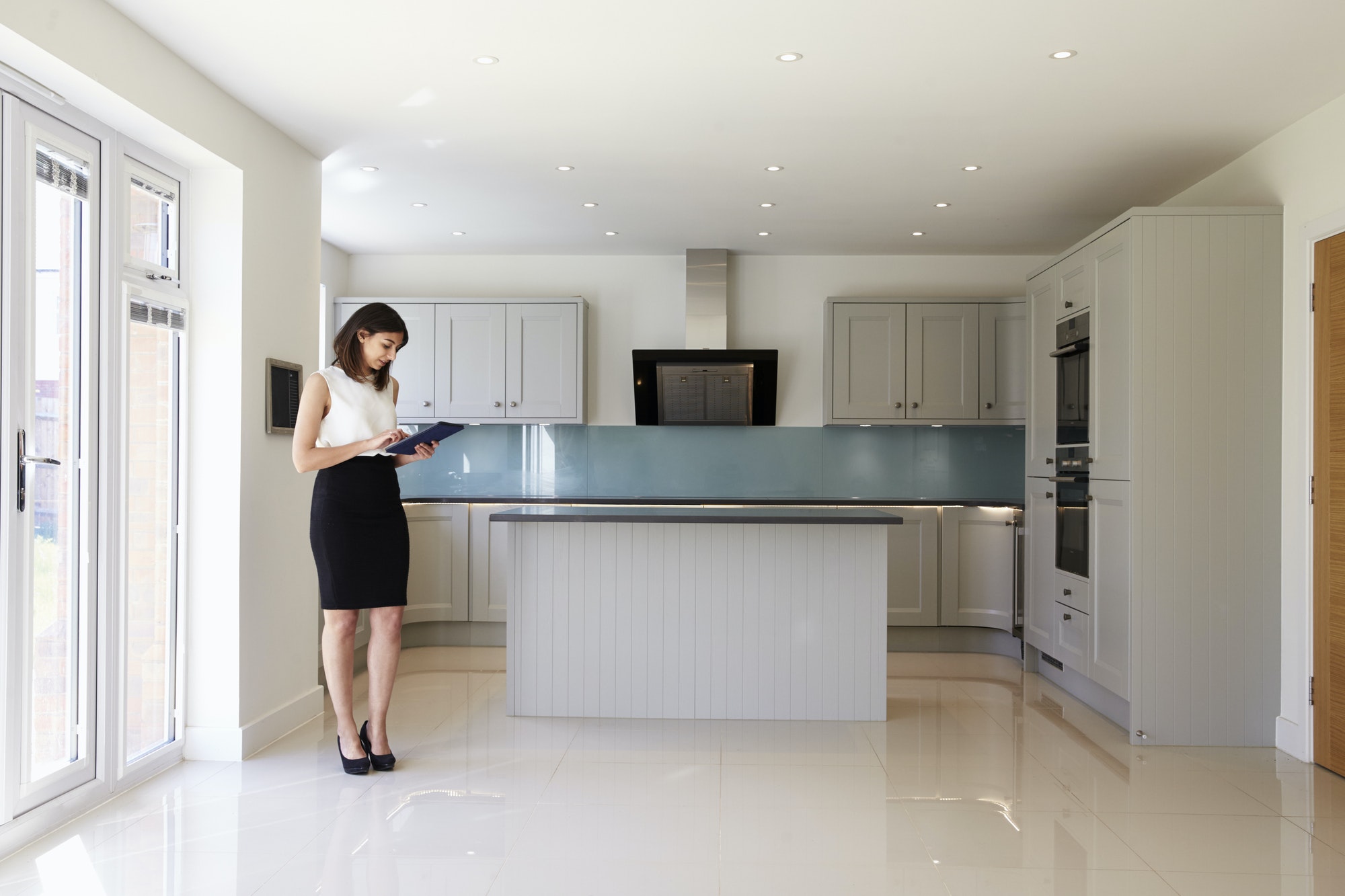 Female Realtor In Kitchen Carrying Out Valuation