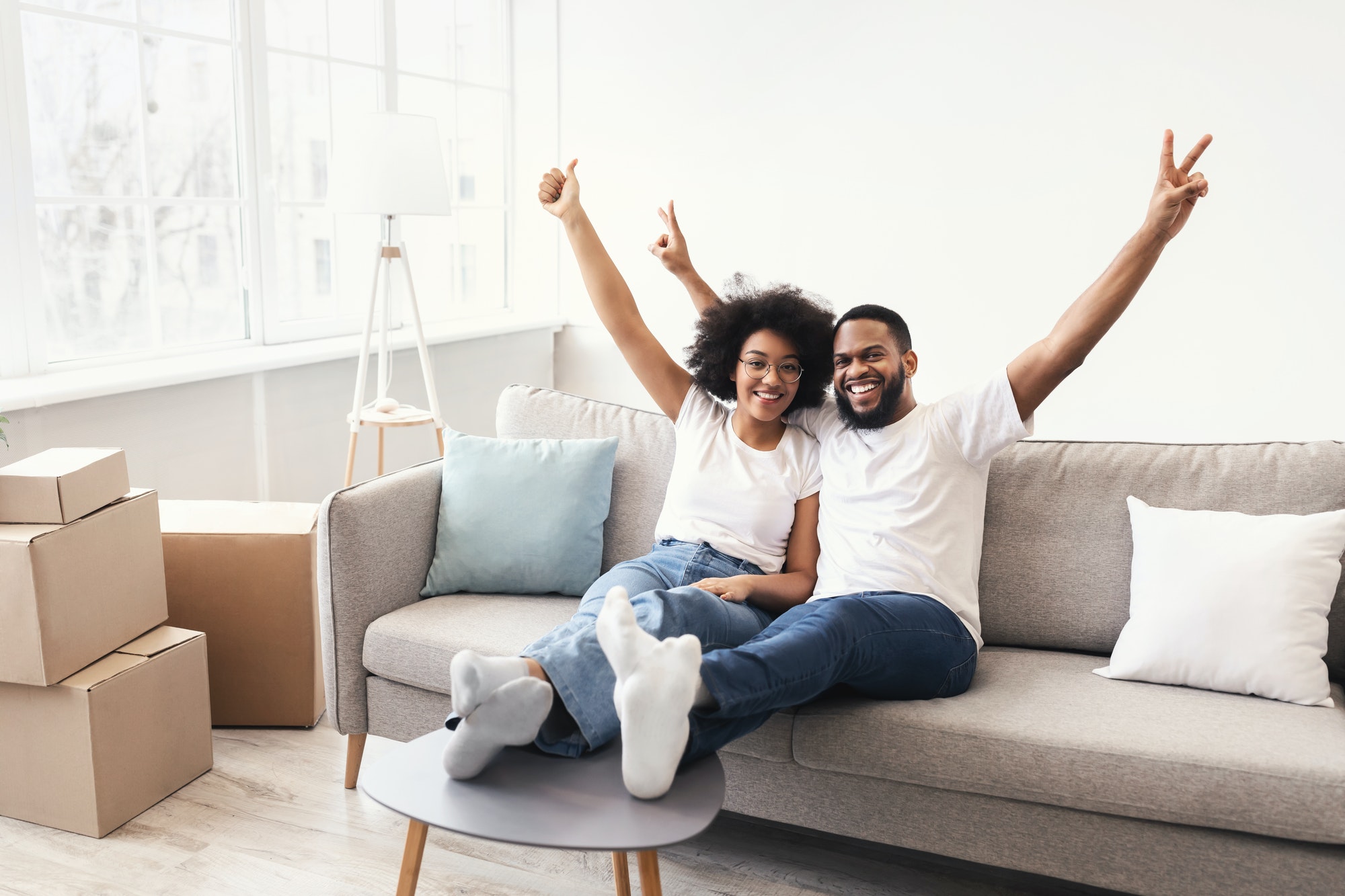 Joyful African Couple Posing Celebrating Real Estate Ownnership Sitting Indoor